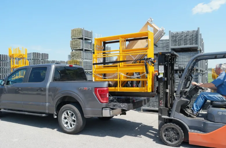 A forklift loads scaffolding equipment into the back of a truck.