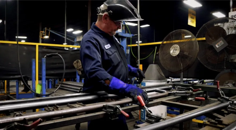A man welds scaffolding together in compliance with OSHA requirements.