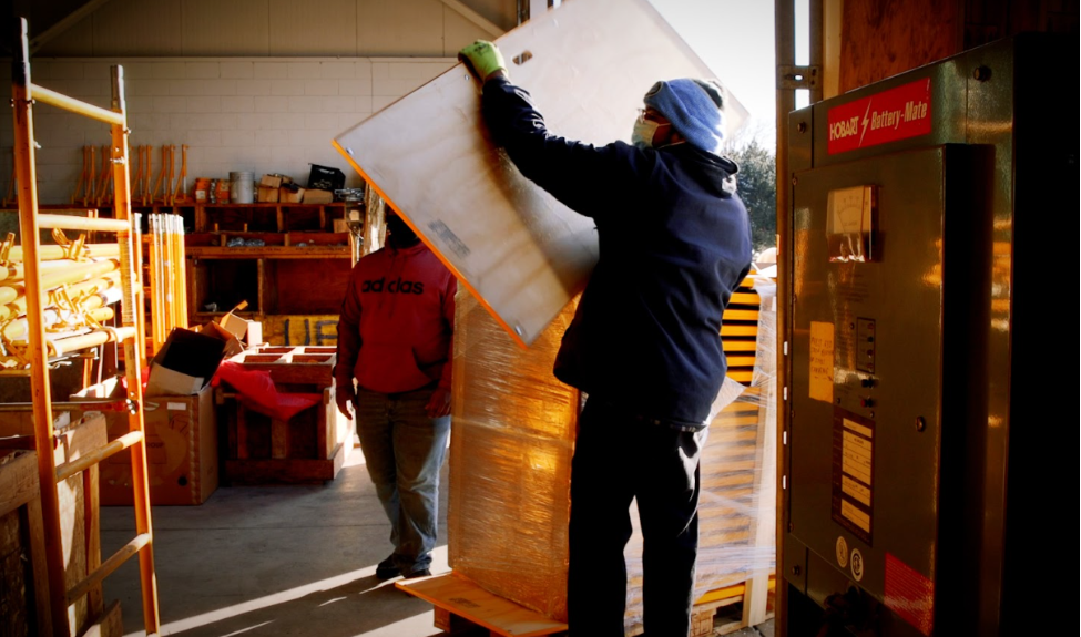 Workers unload Bil-Jax walkboard planks into a warehouse.