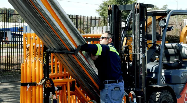 Worker loading aluminum scaffold planks on job site